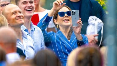 Queen Mary of Denmark takes photos of her son Crown Prince Christian as he sprays champagne from a party bus to celebrate his high school graduation