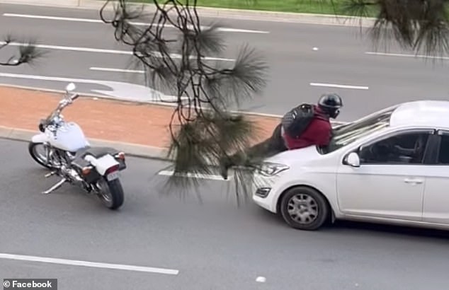 Wild moment when motorcyclist throws himself at a moving car and then hits his head on the window in bizarre road rage incident