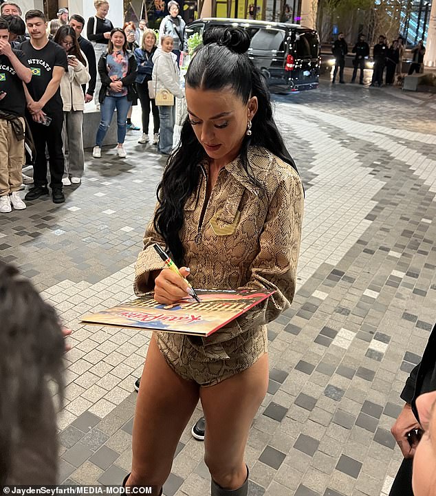 Katy Perry sweetly embraces a young fan as she signs autographs outside her Melbourne hotel after her headlining performance in the AFL Grand Final