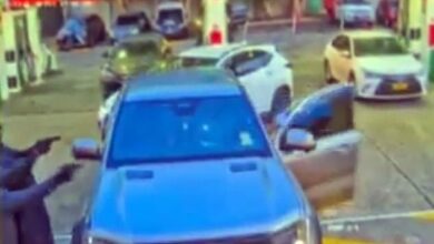 Terrifying footage shows the moment cloaked gunmen open fire on a criminal identity in the busy car park of a Sydney petrol station – as bystanders scream for help